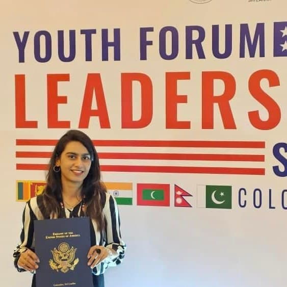 Lalain holding her certificate in front of the Youth Forum Leadership Summit Colombo 2024 banner